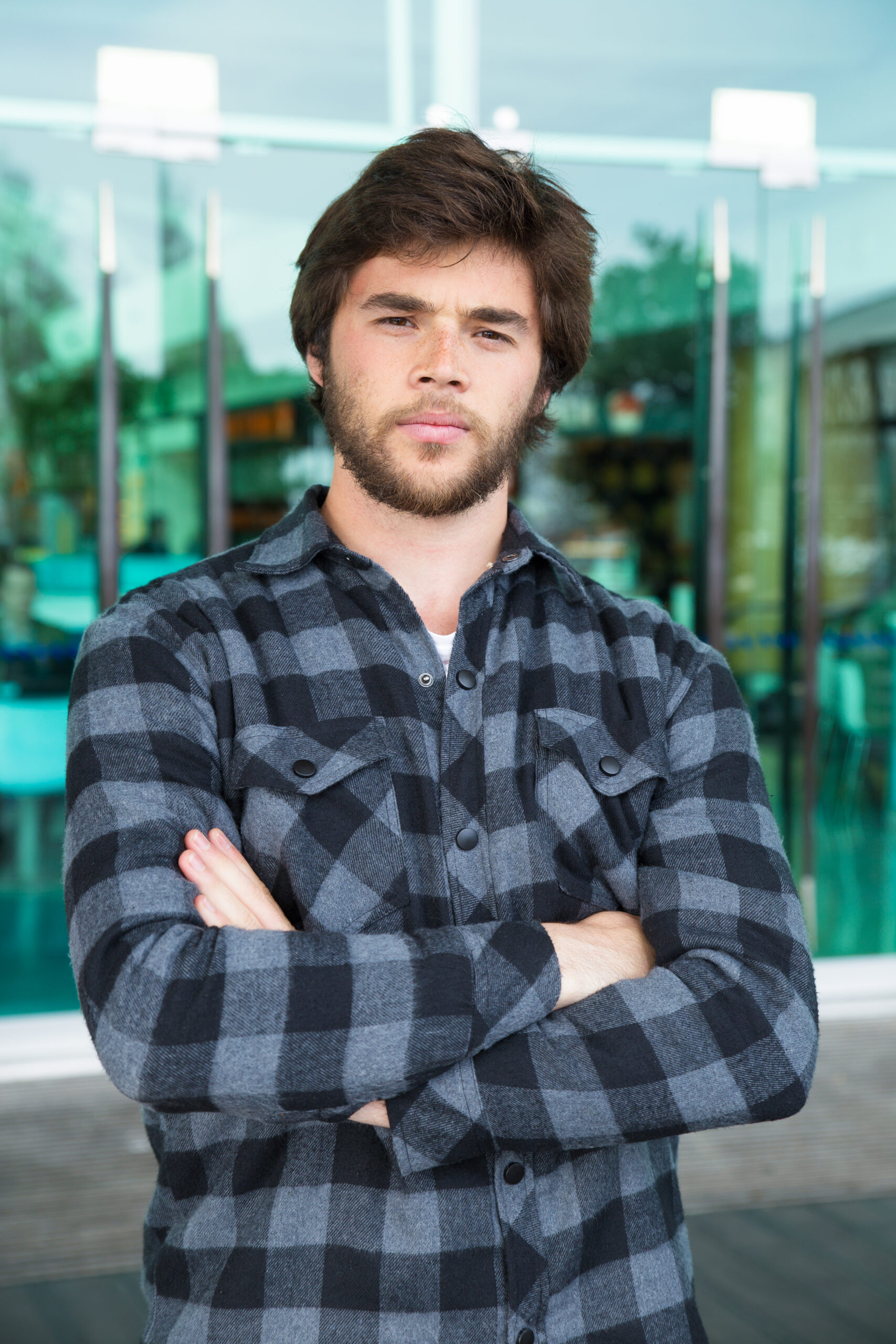 Serious young man standing outdoors with his arms crossed